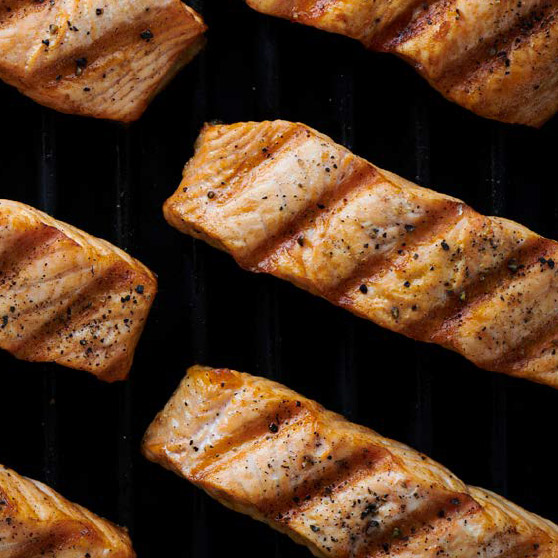 Grillowane filety z łososia z wyraźnymi śladami rusztu i przyprawami – perfekcyjnie przygotowane dzięki CHEF'S COMBI od HOBART, zapewniające równomierne i profesjonalne efekty grillowania.