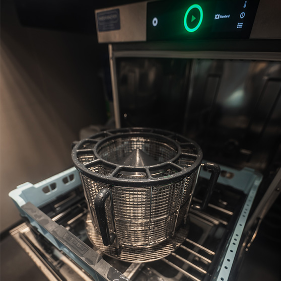 Zbliżenie otwartej podblatowej zmywarki HOBART z okrągłym koszem na sztućce, prezentujące funkcję BESTECK PREMIUM, dzięki której sztućce wychodzą lśniące bez ręcznego polerowania, co oszczędza czas pracy, zapewnia wysoką higienę i charakteryzuje się bardzo niskim zużyciem zasobów.