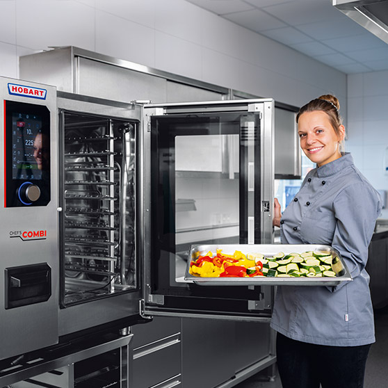 Profesjonalny combi steamer HOBART w nowoczesnej kuchni ze stali nierdzewnej, otwarte drzwi, taca ze świeżymi warzywami jak papryka i cukinia do efektywnego gotowania w gastronomii