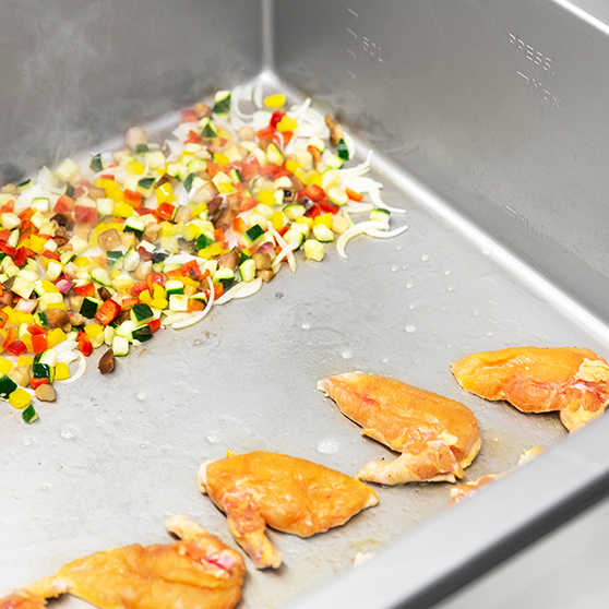 Wnętrze HOBART Precipan z pokrojonymi warzywami i podsmażonym drobiem, wielofunkcyjne urządzenie do technologii gotowania w kuchniach profesjonalnych.