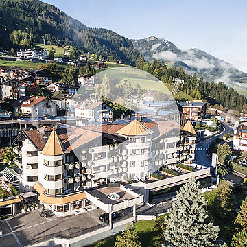 Zdjęcie lotnicze Gardena Grödnerhof w Ortisei, pięciogwiazdkowego hotelu Relais & Châteaux położonego w otoczeniu Dolomitów, znanego z restauracji gourmet Anna Stuben wyróżnionej gwiazdką Michelin i wysokimi ocenami prestiżowych przewodników.