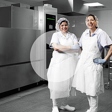 Dwóch pracowników w odzieży higienicznej w strefie zmywania w szpitalu Heinsberg przed przemysłową zmywarką z wózkami ze stali nierdzewnej i nowoczesną technologią higieniczną do efektywnego mycia